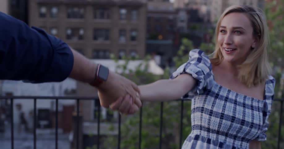 Man and woman kiss while dancing on a building rooftop