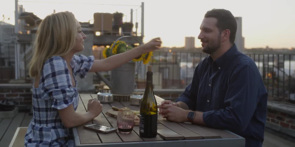 Man and woman sitting outside on a table eating and talking