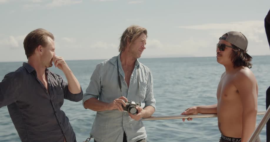 Three men stand in a boat as they talk