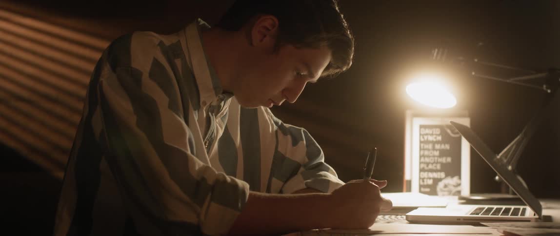 A man is writing at his desk