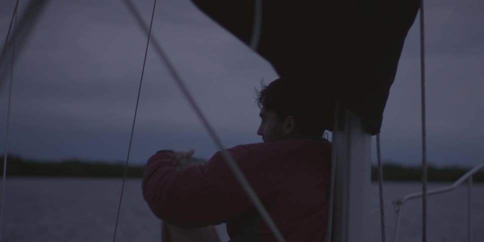 A man sits on a boat while sipping from a mug