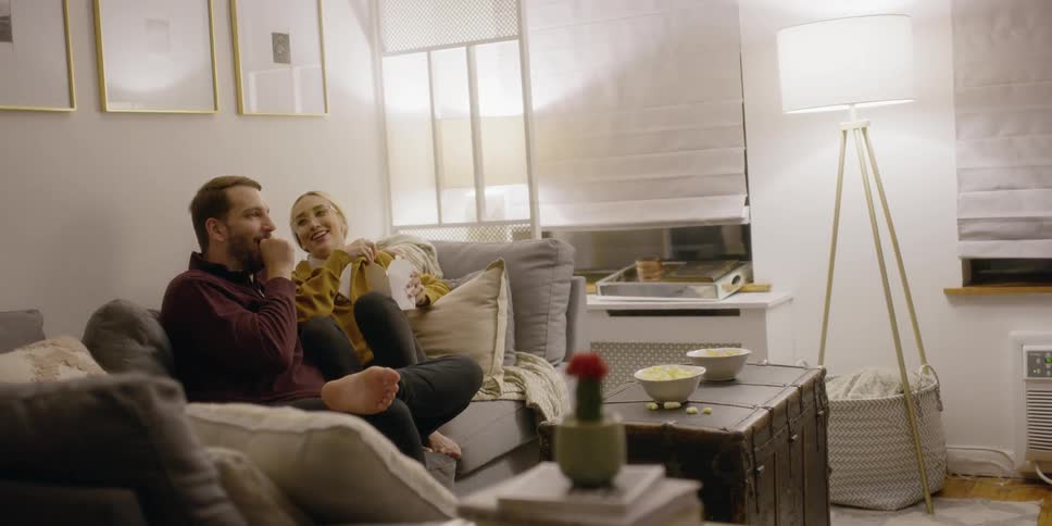 Man and woman sitting on couch talking and laughing