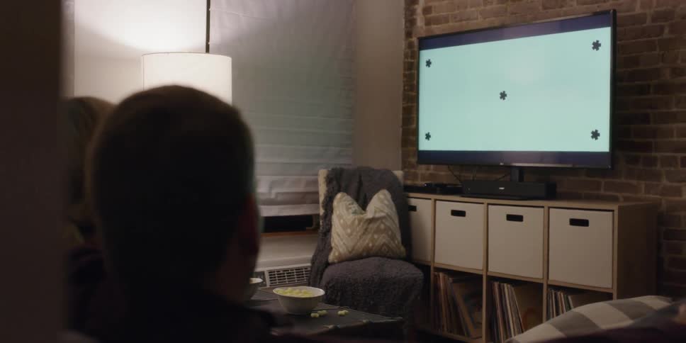 Two people sit and watch television