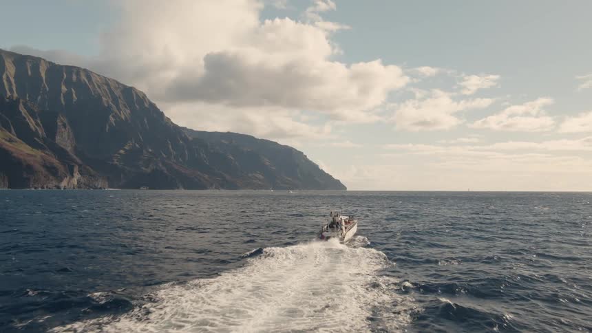 Boat travels in the rough water under a blue sky