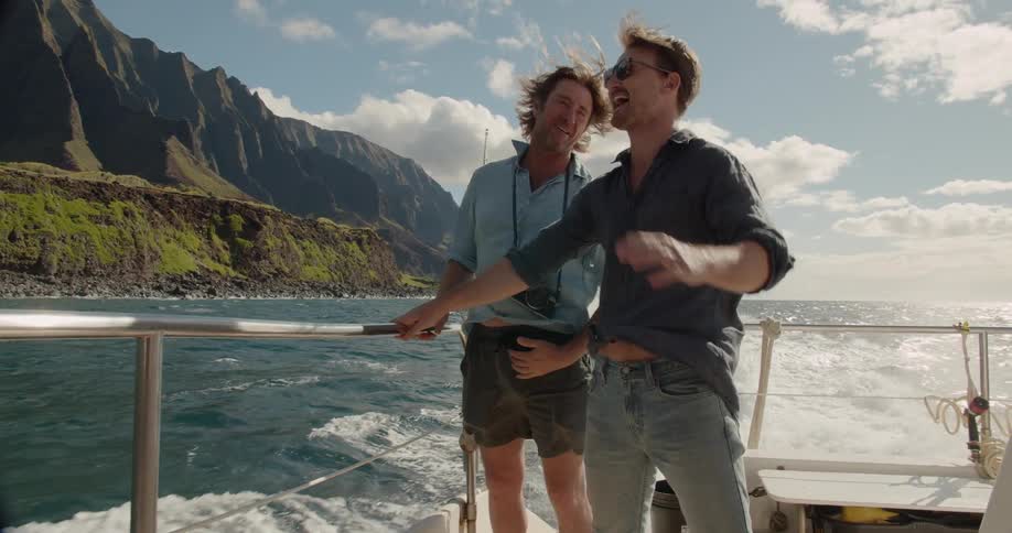 Two men stand in a boat as it travels over the water