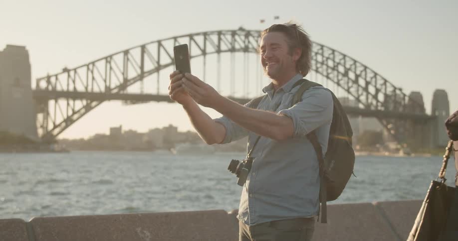 A man takes a selfie outside by the water