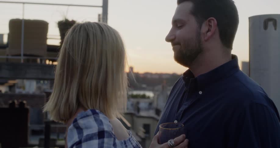 A man and woman drink together on the balcony