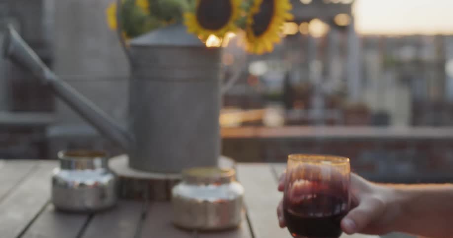 Man and woman drink red wine on a building rooftop at sunset