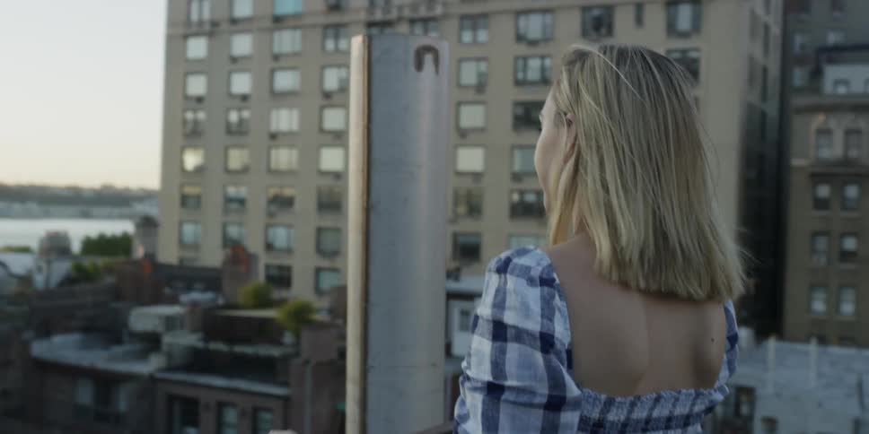 A woman walks to the balcony railing