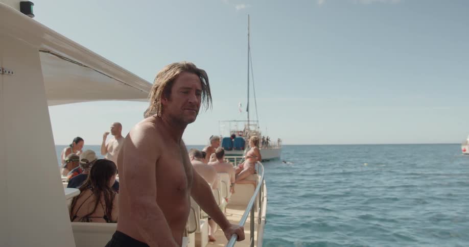 Man leans on the railing of a boat looking out at the water