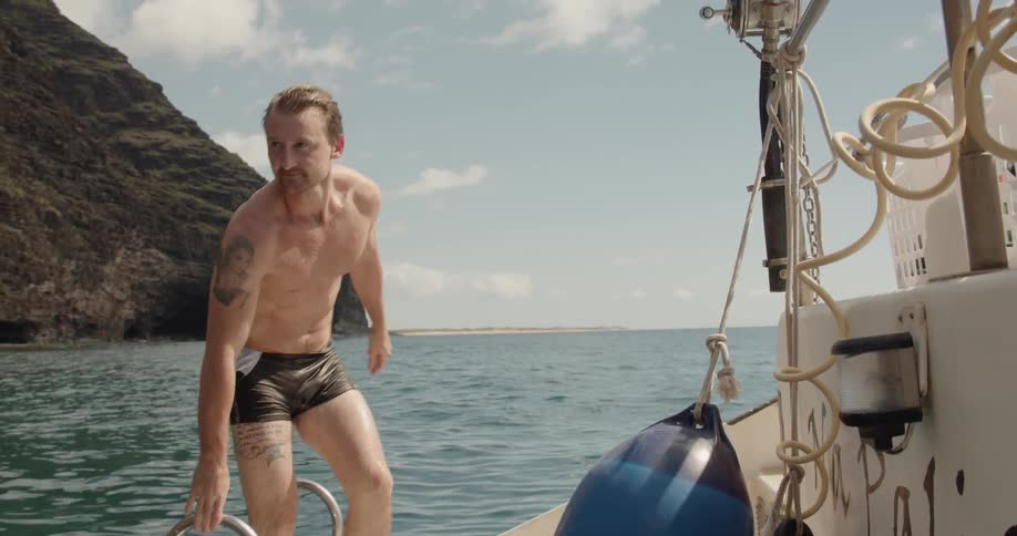 A man climbs up onto a boat from the water