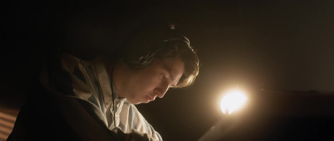 A young man writes with headphones on