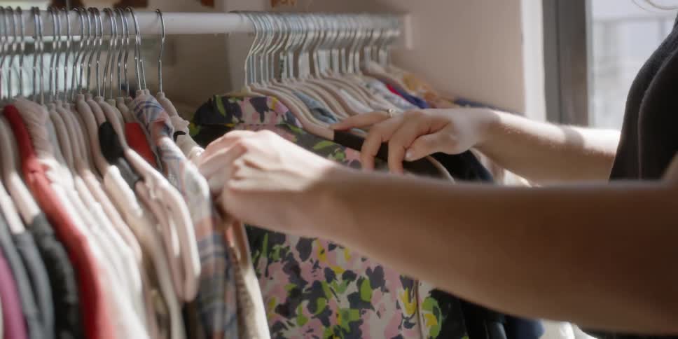 Woman looks through the clothing hanging on hangers