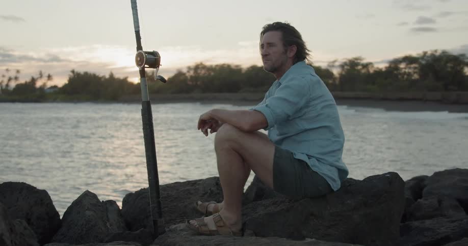 A man fishes near the shore at dawn