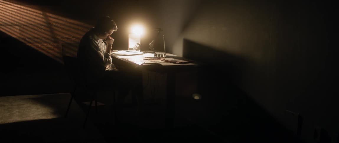 Man sits at a desk writing at night