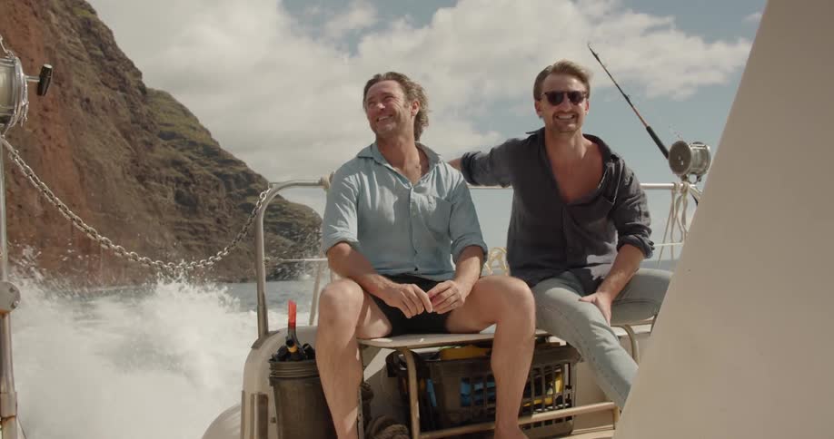 Two men ride on a boat on a windy day