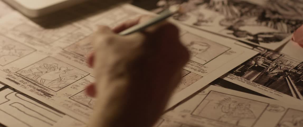 A man uses a pencil on illustrations on the desk