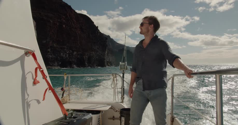 A man is riding on the boat holding onto the railing