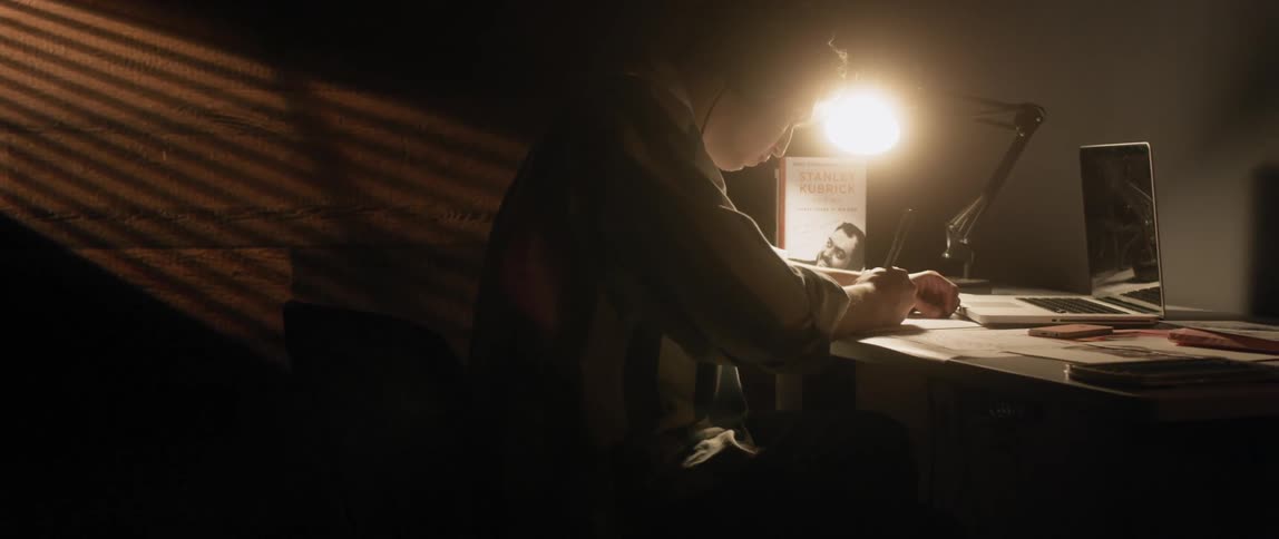 Young man sits at desk writing