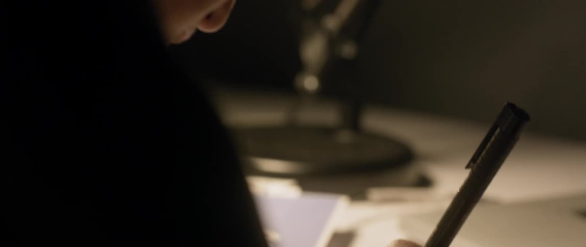 A man doodles while wearing headphones at a desk