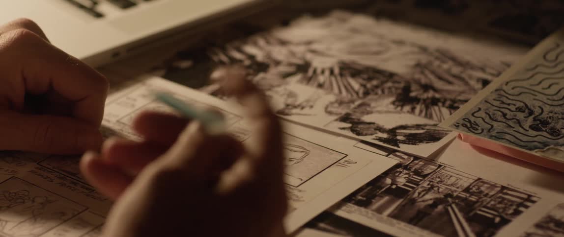 A comic book artists works on a page