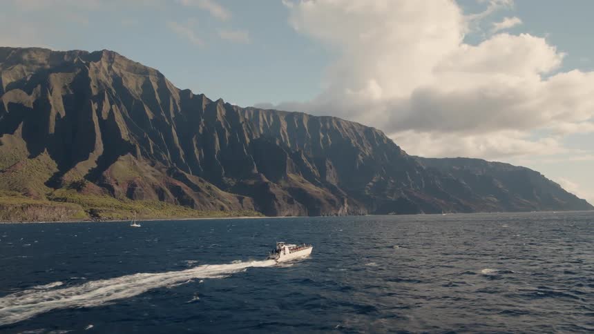 The boat sails in the water by the mountain