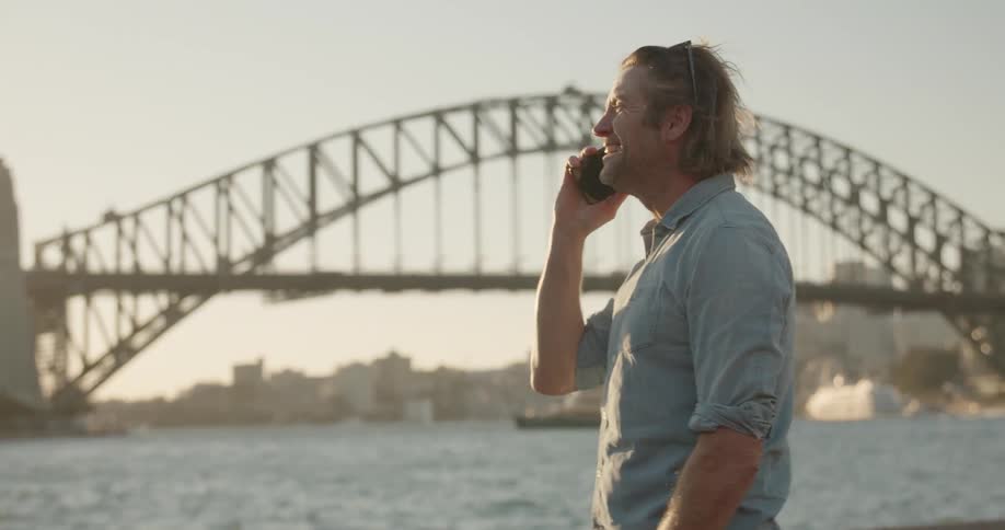 Man stands near urban bridge talking on phone