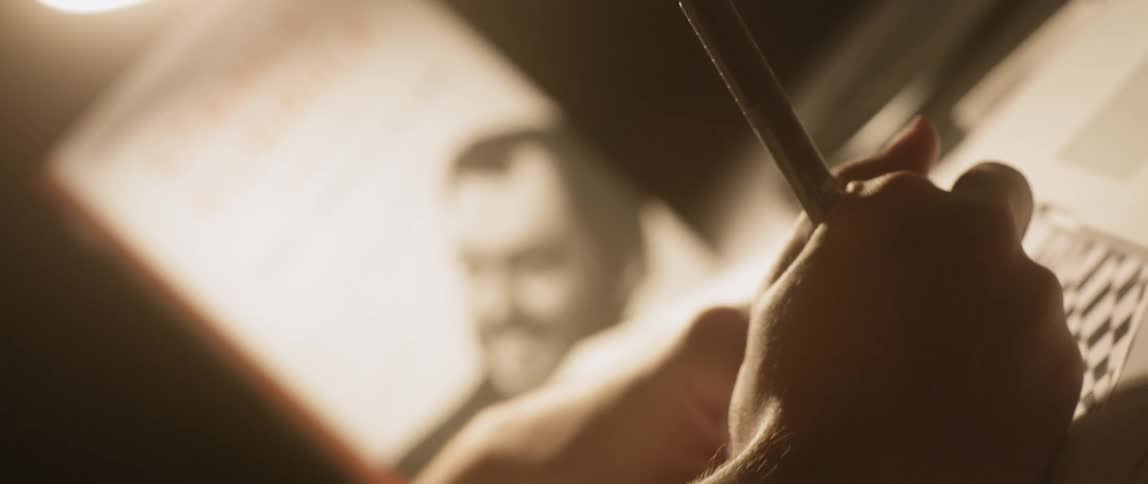 A man is drawing on paper inside in daylight