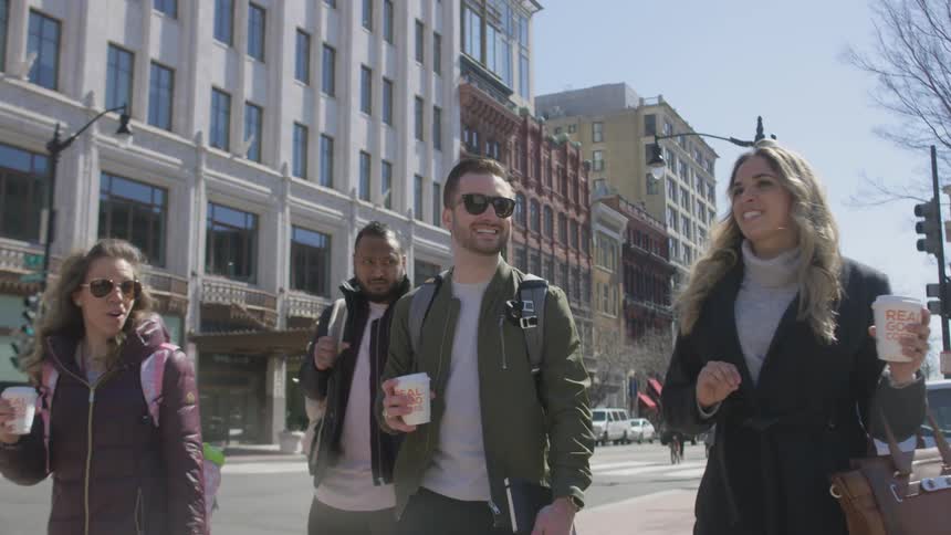 Men and women walking through the city street talking in the afternoon
