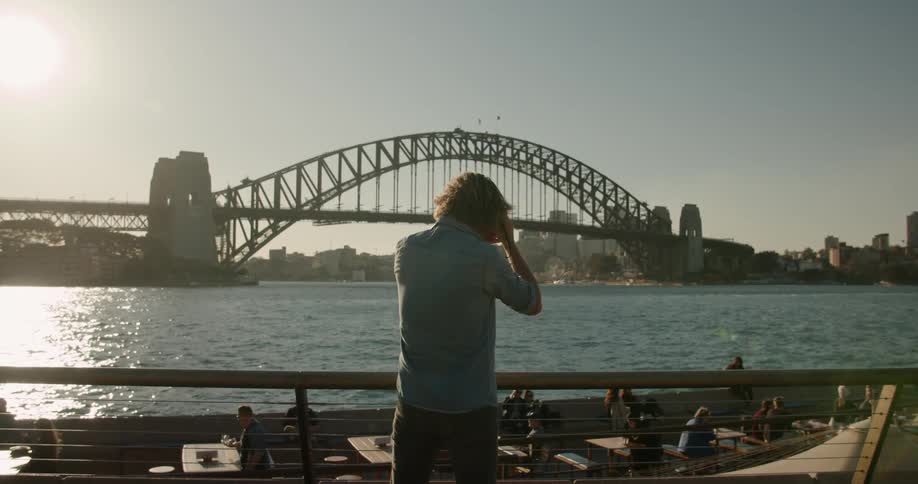 A man is taking pictures of a harbor in an urban setting in daylight