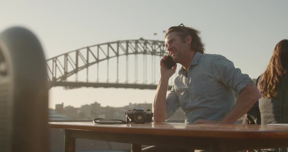 Man talks on a cellphone as a woman sits nearby