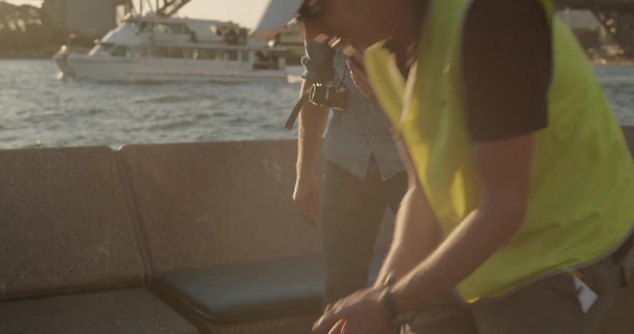 A man pets a dog who runs over by the water