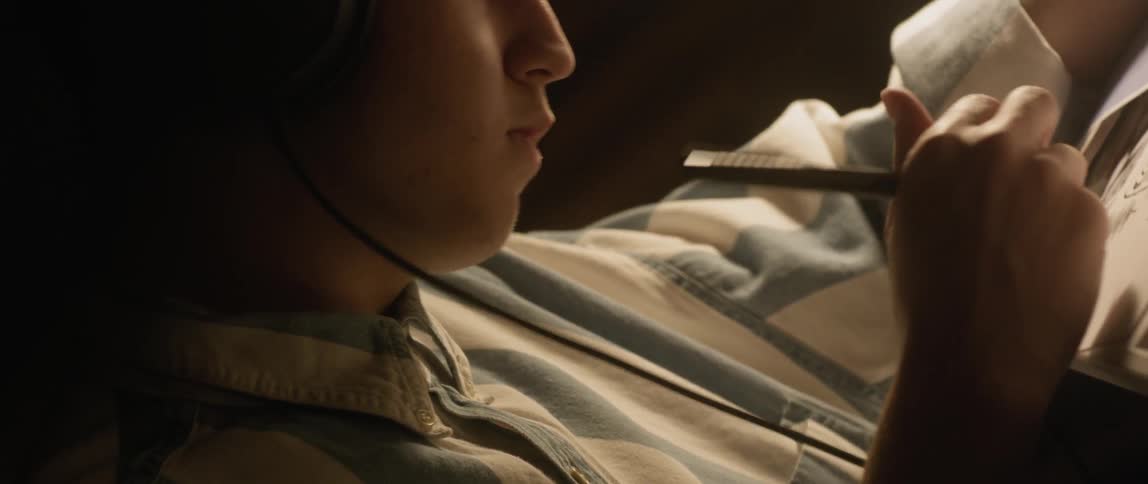 A man is wearing headphones as he writes