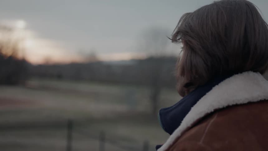 Man stands outside in a rural area at sunset
