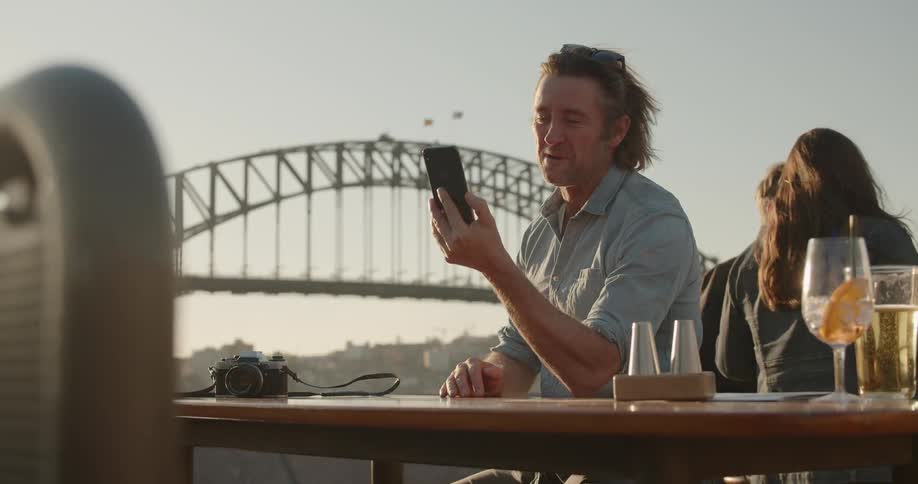 A man takes a selfie near some drinks on a sunny day
