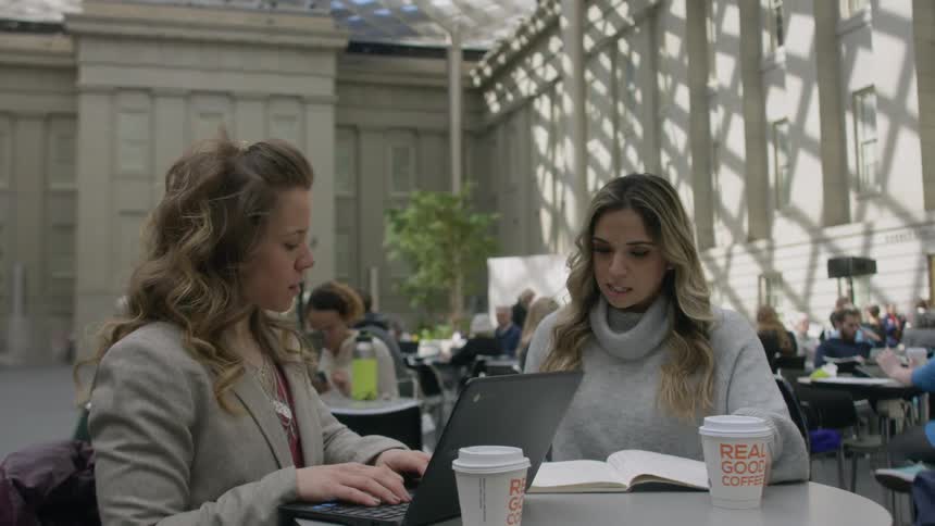 Two women sit together at a table talking