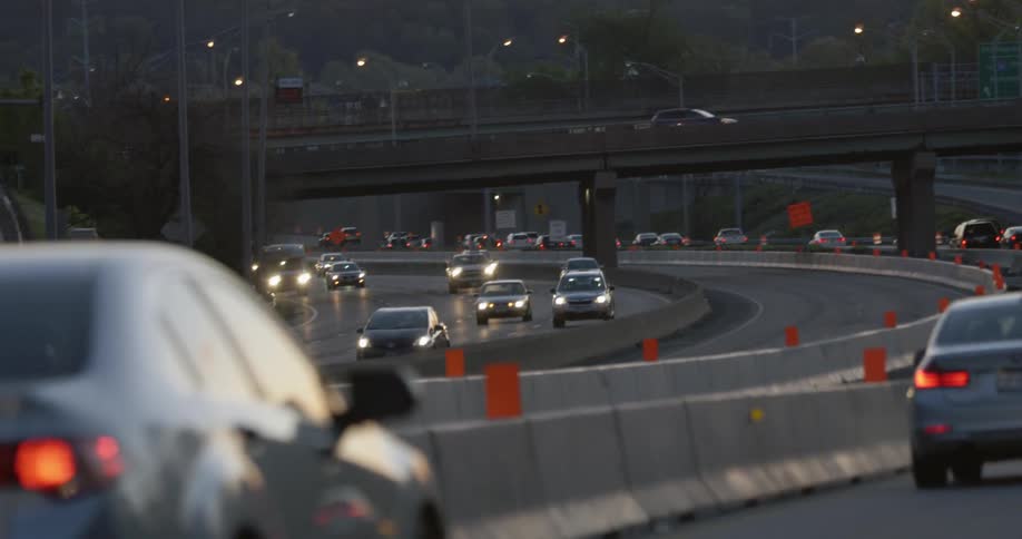 Traffic is flowing on a freeway system at dusk