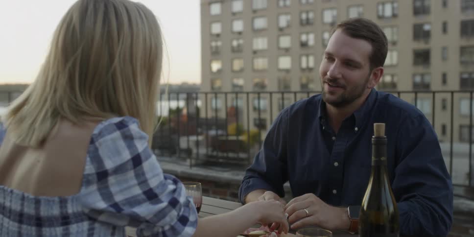 Man and woman sitting outside on a table eating and talking