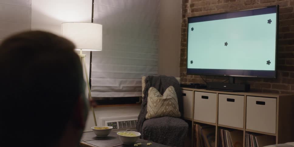 A man and woman sit and watch television