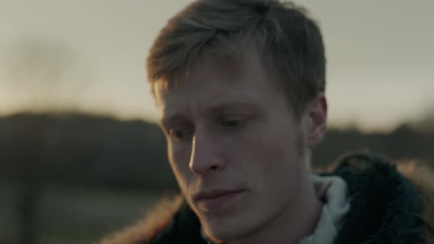 Man stands outside in a field on a sunny day
