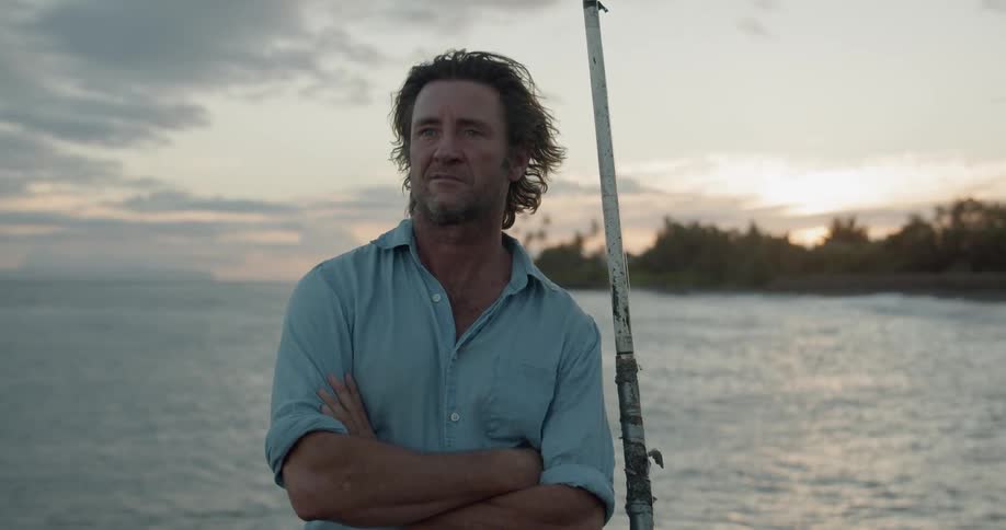 A man stands by the water with a fishing pole