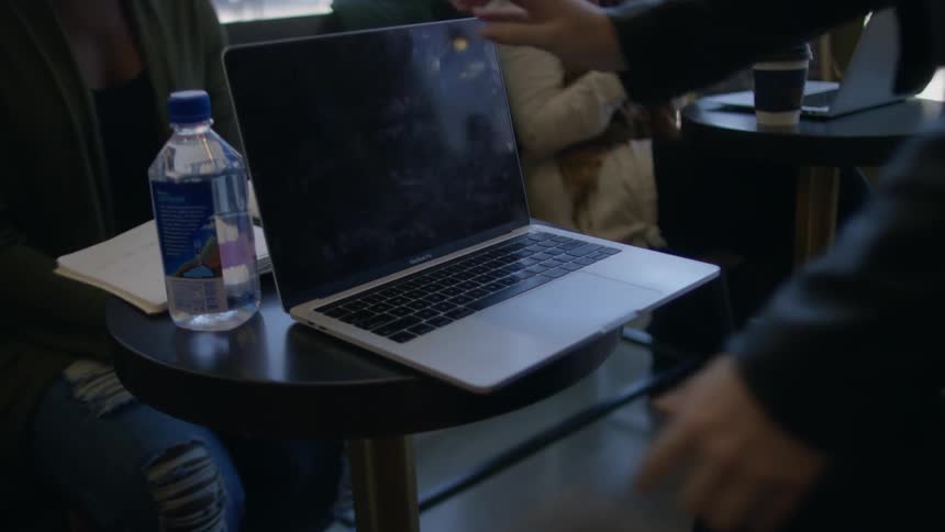 A woman opens a laptop on a cafe table