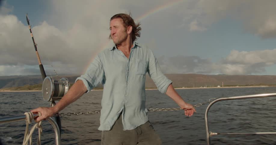 Man fishes on a boat with a rainbow in the background