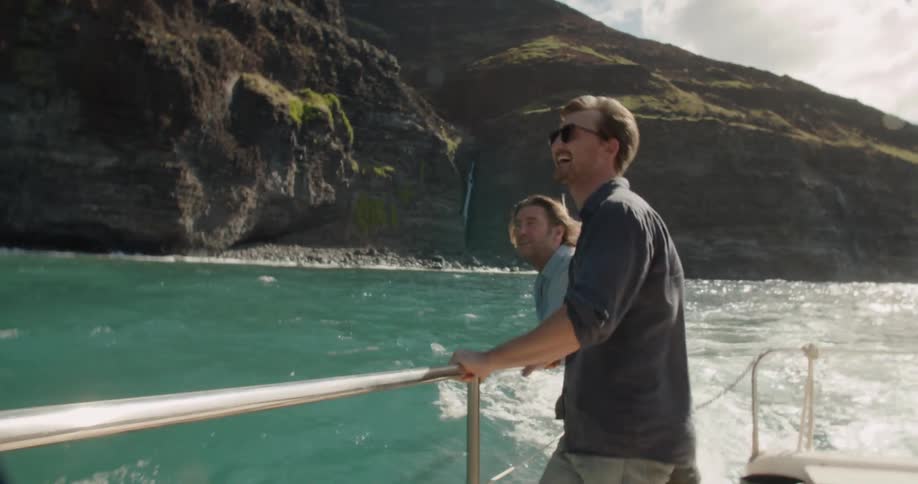Two men ride on the back of a speeding boat