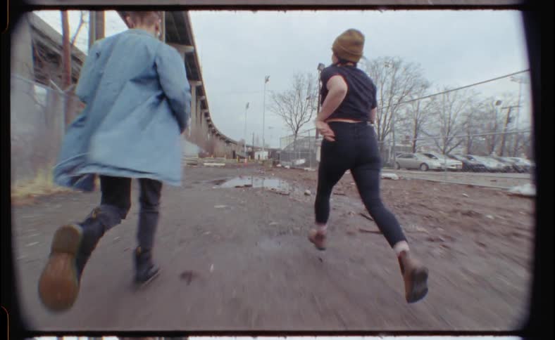 Man and woman run around a puddle next to a fence
