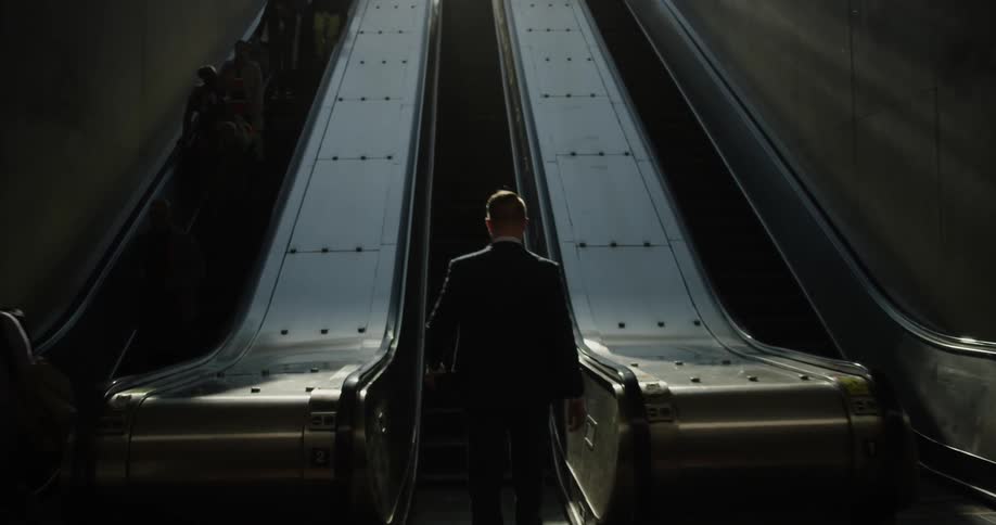 A man walks and gets on the escalator