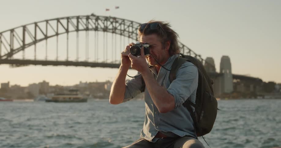 A man takes photographs near the windy shore