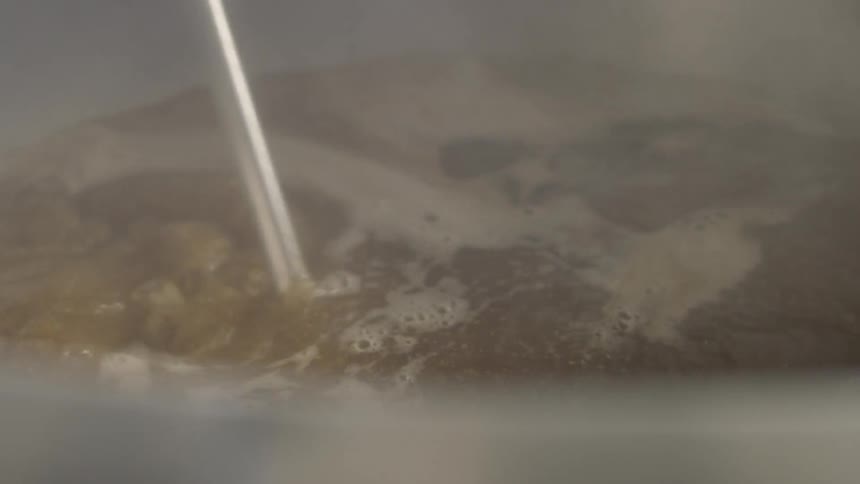 Hot liquid is stirred with a large silver utensil