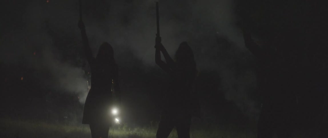 Fireworks exploding and smoke billowing behind people holding roman candles