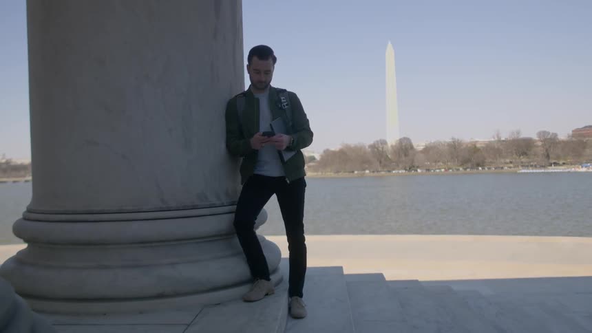 Man leans against a pillar near the washington monument